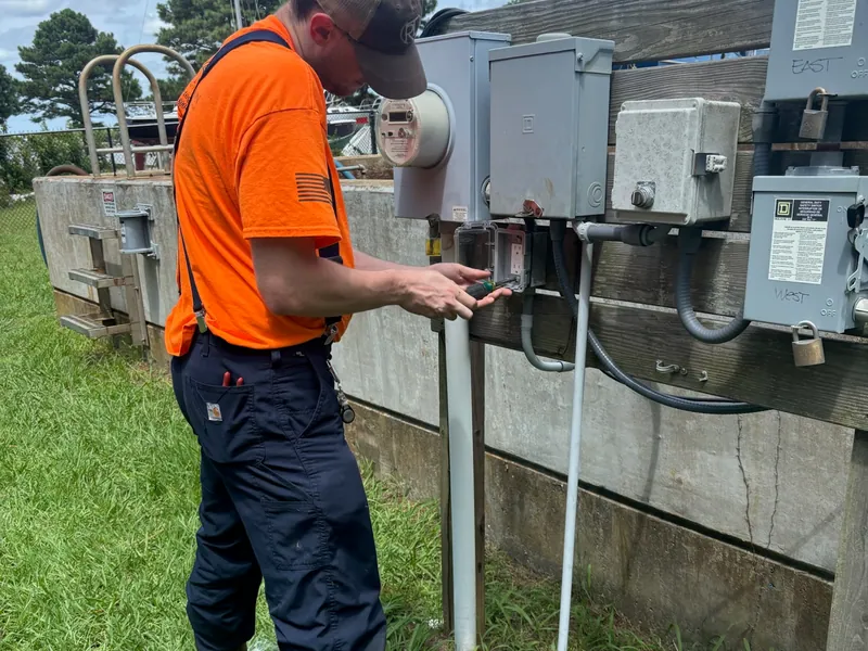 A field technician working at disconnects and control enclosures at an outdoor site