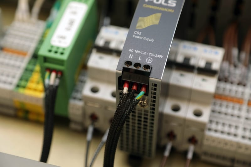 A DIN-rail power supply wired into a control panel