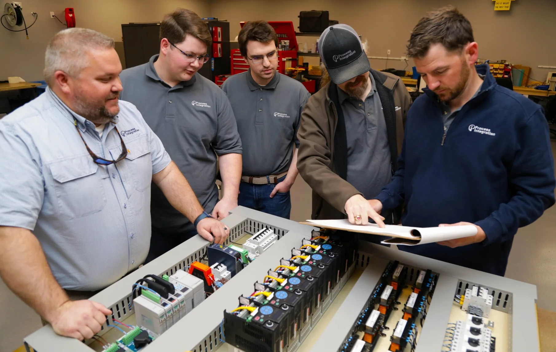 Shorite Controls engineers reviewing drawings over an open control panel